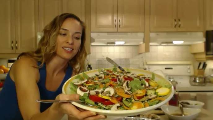 Kimberly presenting a romaine salad with turkey breast, blue potatoes, chèvre and raspberry vinaigrette in her kitchen