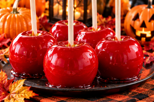 Glossy red homemade candy apples with wooden sticks displayed for National Candy Apple Day.