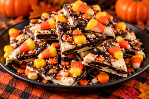 Broken pieces of dark and white chocolate bark decorated with colourful sweets and Halloween sprinkles.